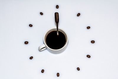 Eine Uhr aus einer Kaffeetasse und -bohnen