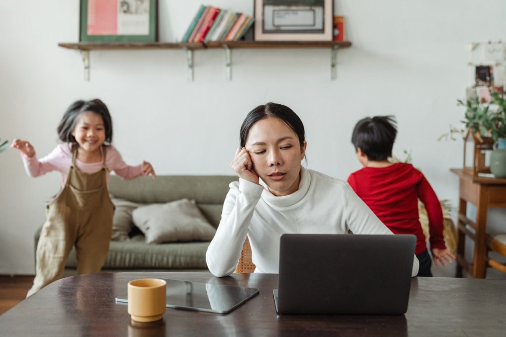Eine Frau ist genervt von ihren Kindern und versucht sich im Home-Office zu konzentrieren.